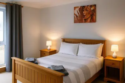 a bedroom with a bed with two lamps and a window at 3 Bed Bungalow - Sleeps 6 - Pet Friendly - Parking in Drummore