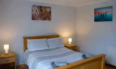 a bedroom with a bed with two lamps on two tables at 3 Bed Bungalow - Sleeps 6 - Pet Friendly - Parking in Drummore