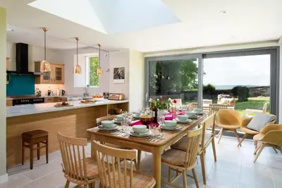 a kitchen and dining room with a wooden table and chairs at Beltie Lodge in Borgue