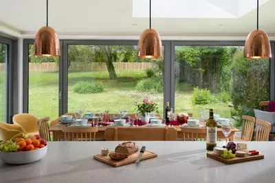 a kitchen and dining room with a table with food at Beltie Lodge in Borgue