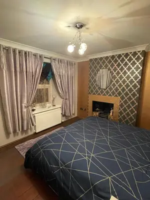 a bedroom with a blue bed and a fireplace at Flosh Cottage Lake District in Cleator