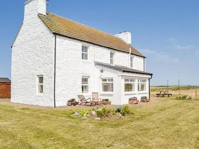 a white house sitting on top of a grass field at Mullhill in Ardwell