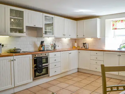 a white kitchen with white cabinets and a window at Mullhill in Ardwell