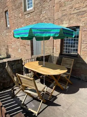 a wooden table and chairs with an umbrella at Kitty’s Place, Apartment, Eden Valley, Cumbria in Brampton