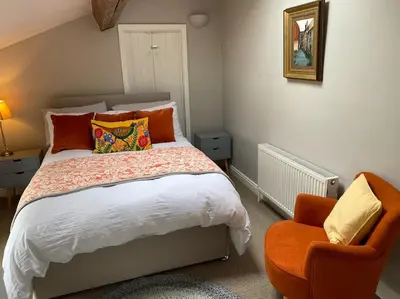 a bedroom with a bed and an orange chair at Kitty’s Place, Apartment, Eden Valley, Cumbria in Brampton