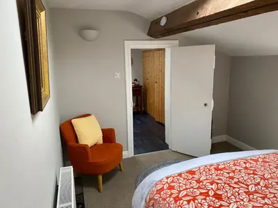a bedroom with a bed and a chair next to a door at Kitty’s Place, Apartment, Eden Valley, Cumbria in Brampton