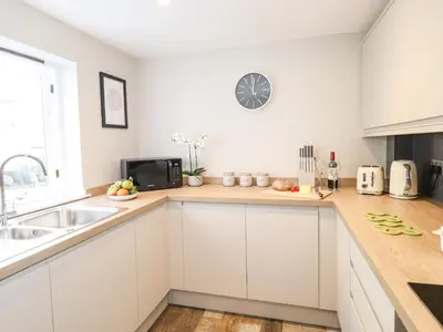 a kitchen with white cabinets and a clock on the wall at Dovestones in Keswick