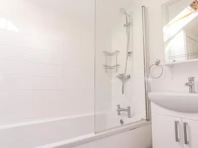 a white bathroom with a shower and a sink at Dovestones in Keswick