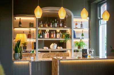 a bar with a counter with bottles on shelves at Fellpack House in Keswick