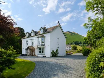 a white house with a hill in the background at Swinside Lodge in Keswick