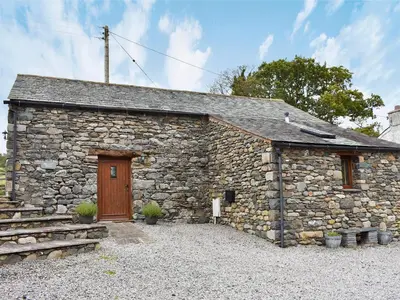 a stone building with a wooden door and stairs at Hilltoft Barn in Dockray