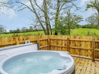 a hot tub on a deck next to a wooden fence at Starling Lodge - Uk31071 in Westward