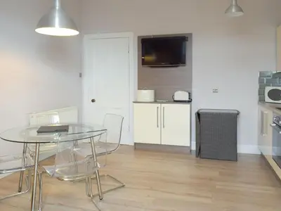 a dining room with a glass table and a kitchen at Charlotte Street in Ayr