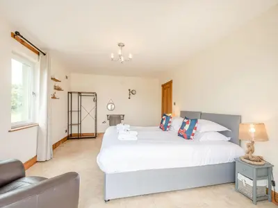 a bedroom with a large white bed and a chair at Seaviews And Hot Tub At Admirals Anchor in Portpatrick
