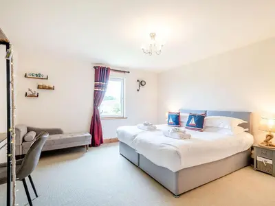 a bedroom with a bed and a couch and a window at Seaviews And Hot Tub At Admirals Anchor in Portpatrick