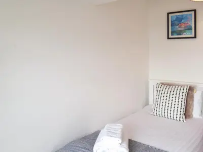 a white bedroom with a bed and a pillow at Southcroft Lodge in Whiting Bay