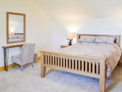 a bedroom with a bed and a mirror and a chair at West Lanegate Farmhouse in Amisfield Town