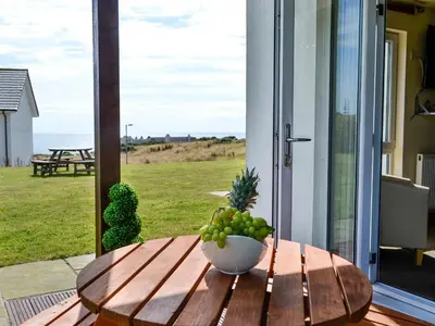 a bowl of fruit on a wooden table on a porch at Seaviews And Hot Tub At The Fairways - Uk39821 in Portpatrick