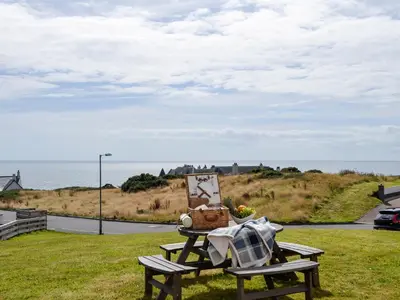 a picnic table with a painting and a basket on it at Seaviews And Hot Tub At The Fairways - Uk39821 in Portpatrick