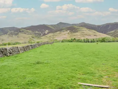 a field of green grass with mountains in the background at Doddick Beck - Uk39153 in Threlkeld