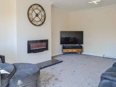 a living room with a tv and a clock on the wall at Park Lane in Auldgirth