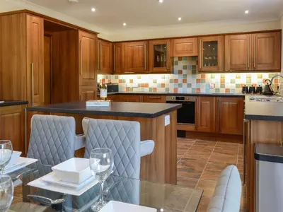 a kitchen with wooden cabinets and a table with wine glasses at Park Lane in Auldgirth