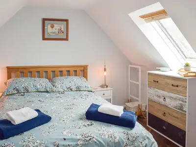 a bedroom with a bed with two blue pillows on it at Seacliffe in Kildonan
