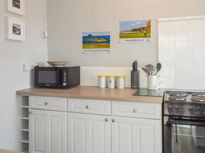 a kitchen with white cabinets and a black microwave at Seacliffe in Kildonan