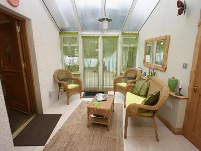 a living room with wicker chairs and a table at Gardener's Cottage in Girvan