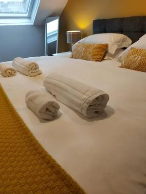 a bed with two towels on top of it at Hill Street Cottage in Portpatrick