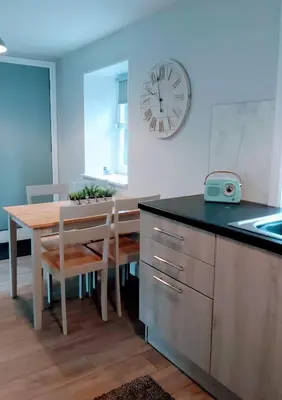 a kitchen with a table and a clock on the wall at Hill Street Cottage in Portpatrick