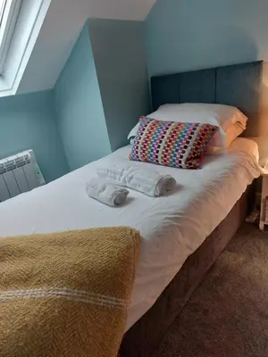 a bed with two pillows and two towels on it at Hill Street Cottage in Portpatrick