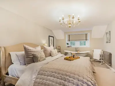 a bedroom with a large bed and a bath tub at Keepers Cottage in Durisdeer