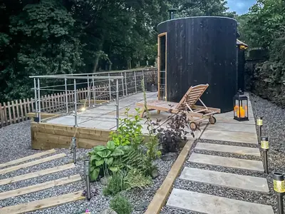 a deck with a wooden chair and a building at Keepers Cottage in Durisdeer