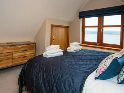 a bedroom with a bed and a dresser and a window at Kringlands in Stranraer