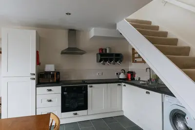 a kitchen with white cabinets and a staircase at ELM HOUSE COTTAGE - 2 Bed Cottage in High Hesket on the edge of the Lake District, Cumbria in High Hesket