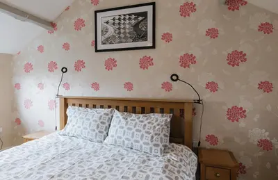 a bedroom with a bed with pink flowers on the wall at ELM HOUSE COTTAGE - 2 Bed Cottage in High Hesket on the edge of the Lake District, Cumbria in High Hesket