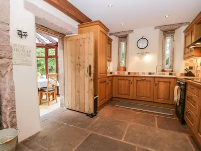 a large kitchen with wooden cabinets and a door at The Lodge in Penrith