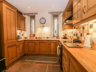 a kitchen with wooden cabinets and a clock on the wall at The Lodge in Penrith