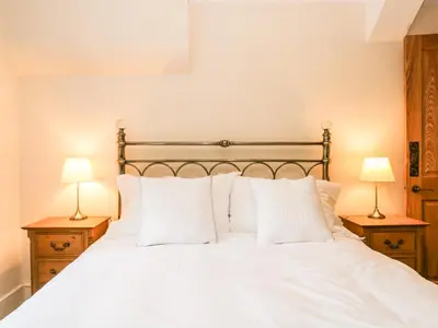 a bedroom with a white bed with two lamps at The Lodge in Penrith