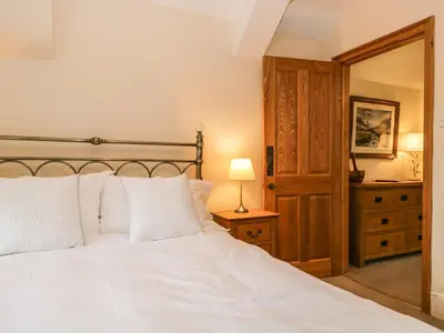 a bedroom with a white bed with a lamp and a dresser at The Lodge in Penrith