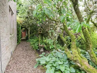 a garden with a bird house next to a tree at The Lodge in Penrith