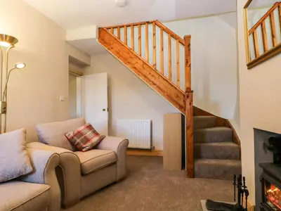 a living room with a staircase and a couch at Fellside Cottage in Cockermouth