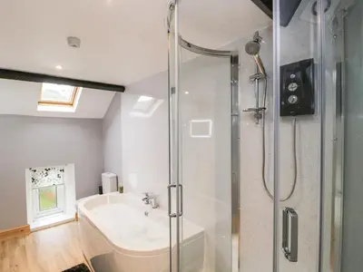 a bathroom with a shower and a tub and a sink at Fellside Cottage in Cockermouth