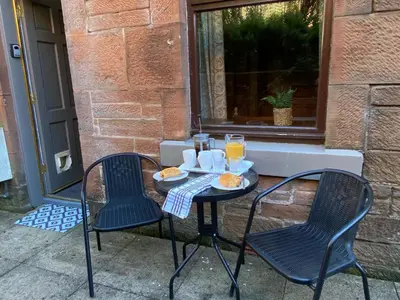 a table with two chairs and two glasses of orange juice at Beautiful Apartment - Outstanding Central Location - Pass the Keys in Dumfries