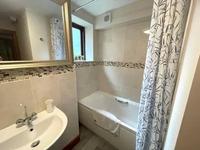 a bathroom with a tub and a sink and a bath tubermottermott at Beautiful Apartment - Outstanding Central Location - Pass the Keys in Dumfries