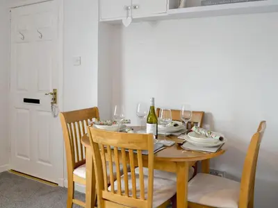 a dining room table with a bottle of wine on it at Number 7 in Gatehouse of Fleet