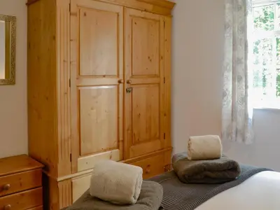 a bedroom with a wooden cabinet and two chairs at Number 7 in Gatehouse of Fleet