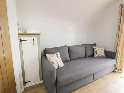 a gray couch with pillows in a room at Laird Lodge 4 in Lockerbie