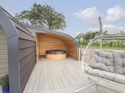 a deck with a swing and a fire pit at Laird Lodge 5 in Lockerbie